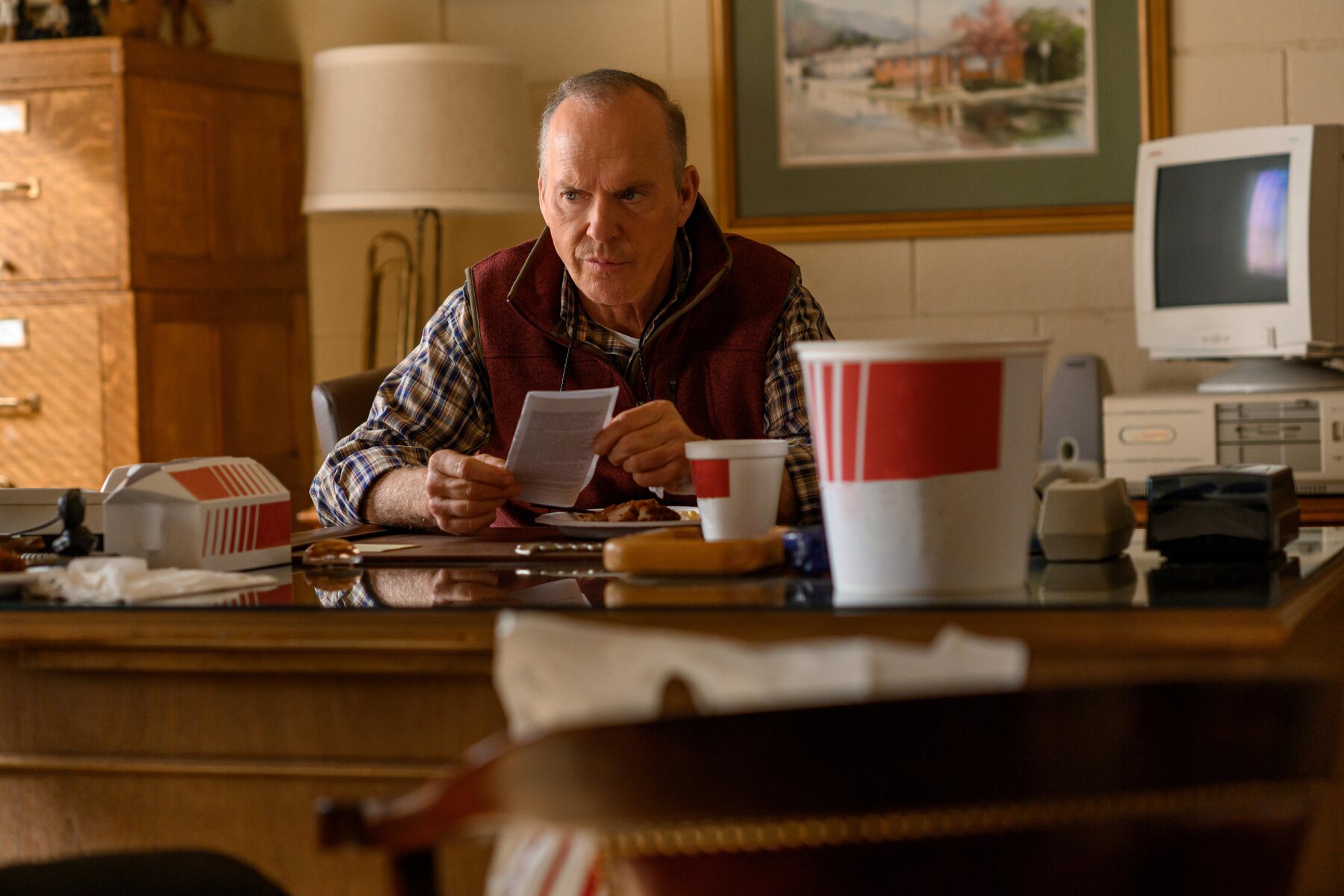 Man sitting at desk looking concerned. Surrounded by fast food containers.